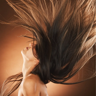 Image d'une femme aux cheveux longs rejetant sa tête en arrière, ses cheveux volant gracieusement, symbolisant les soins capillaires proposés par la marque Rose & Jules