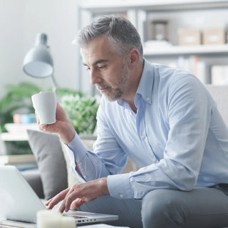 Image montrant un homme buvant un café tout en consultant son ordinateur portable, évoquant concentration et travail efficace.