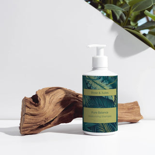 Flacon de face du shampoing hydratant "Pure Balance" de Rose et Jules, bio, vegan et naturel, mis en valeur en studio devant une branche de bois rouge.